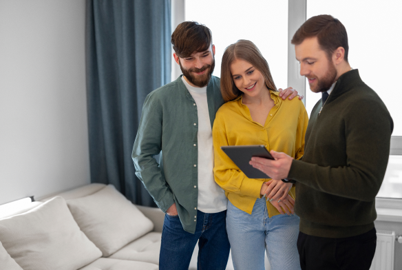 Three individuals in a modern office setting, actively engaging in a discussion while utilizing technology tools such as a tablet and a smartphone. The scene exudes a collaborative atmosphere that hints at the seamless integration of a cutting-edge property management solution like Neo, enhancing and simplifying the real estate experience.