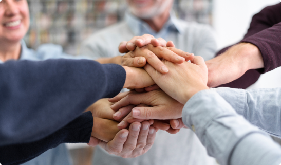 A group of people with their hands stacked together, symbolizing unity or teamwork.