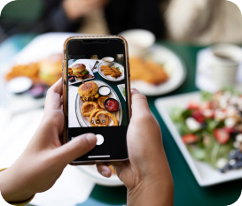 A person capturing a picture of a selection of dishes on a table using a smartphone.