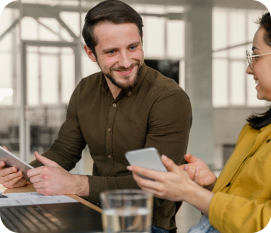 Two professionals collaborating in an office setting, one using a tablet and the other a smartphone.